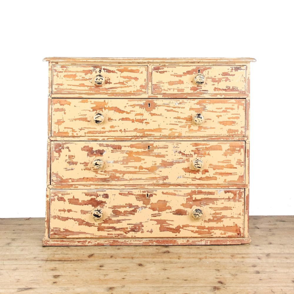 An antique Victorian painted pine chest of drawers featuring two short over three long drawers with turned wooden knobs and a heavily distressed cream paint finish.