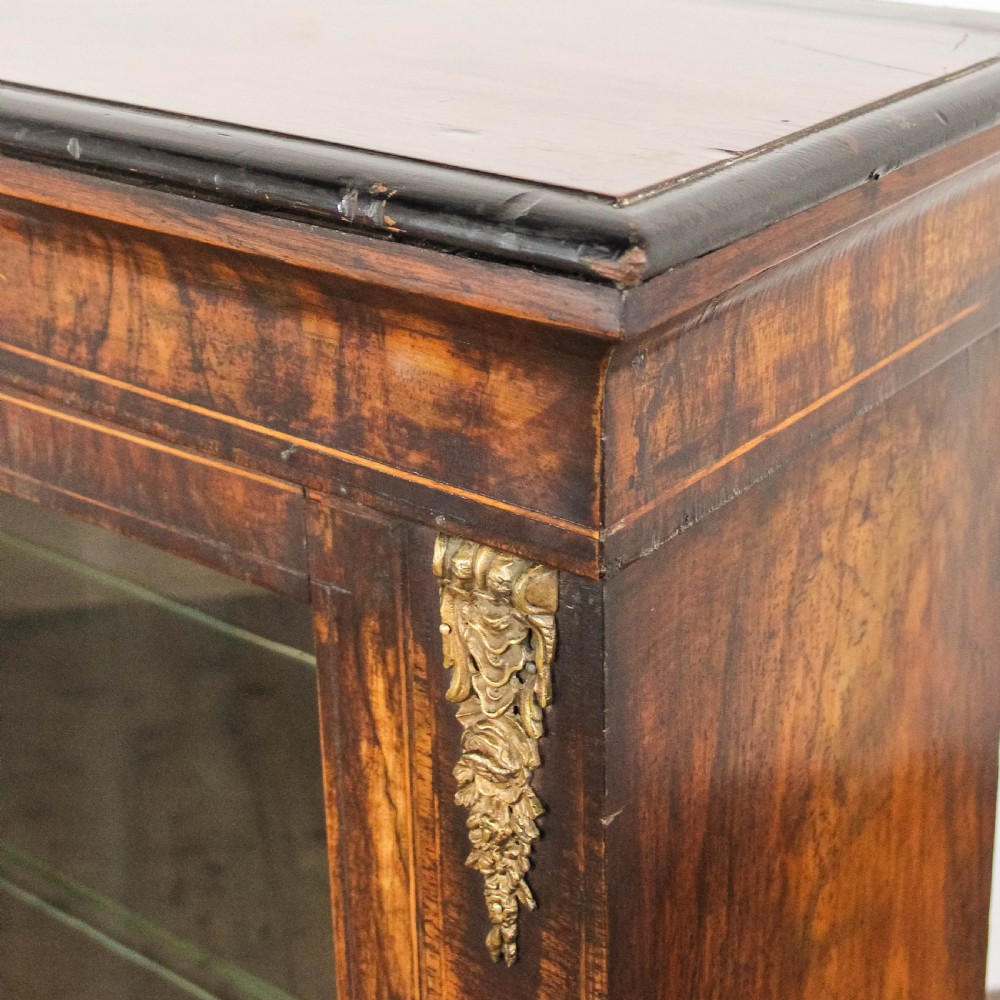 An antique Victorian walnut pier cabinet featuring twin glazed doors, floral boxwood marquetry inlay, and decorative ormolu brass mounts. View V