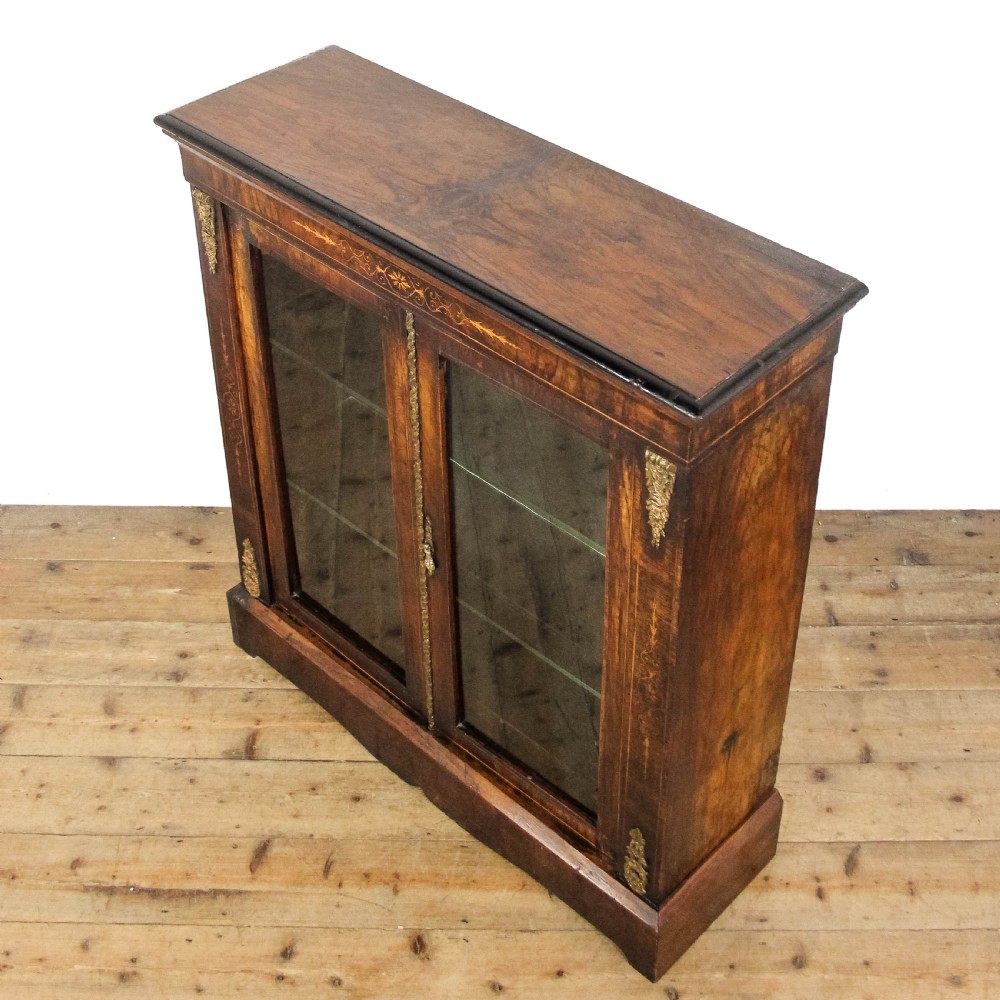 An antique Victorian walnut pier cabinet featuring twin glazed doors, floral boxwood marquetry inlay, and decorative ormolu brass mounts. View VI