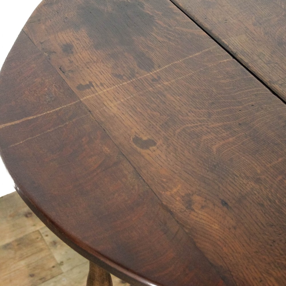 An antique dark oak gateleg table featuring two hinged drop leaves, turned legs, lower stretchers, and a single end drawer with a brass handle. View VIII
