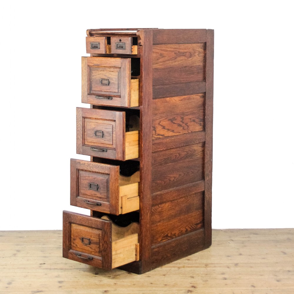 A tall early 20th-century oak filing cabinet featuring panelled sides, four large drawers, two small top drawers, and metal pull handles. View II