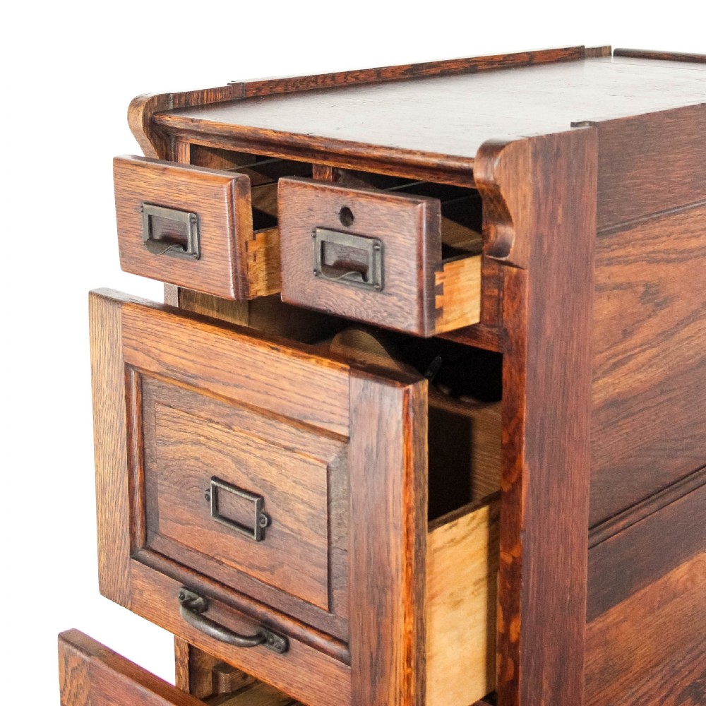 A tall early 20th-century oak filing cabinet featuring panelled sides, four large drawers, two small top drawers, and metal pull handles. View III