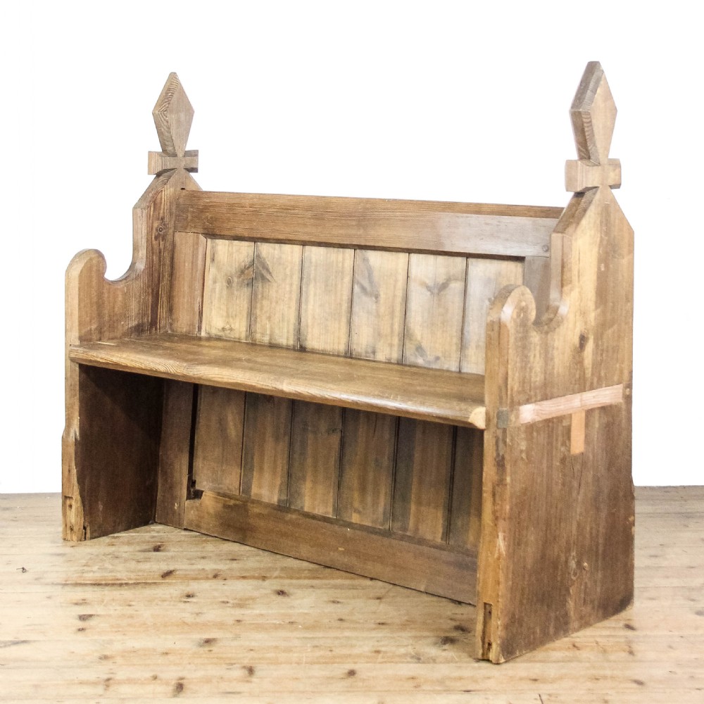 An antique pine church pew featuring vertical plank back panels and shaped bench ends topped with carved finials. View II