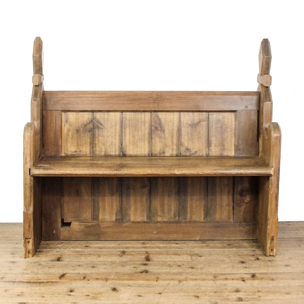 An antique pine church pew featuring vertical plank back panels and shaped bench ends topped with carved finials. View III