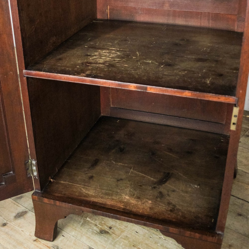 A pair of matching 19th-century mahogany side cabinets with flame mahogany door panels, single upper drawers, and shaped bracket feet. View V