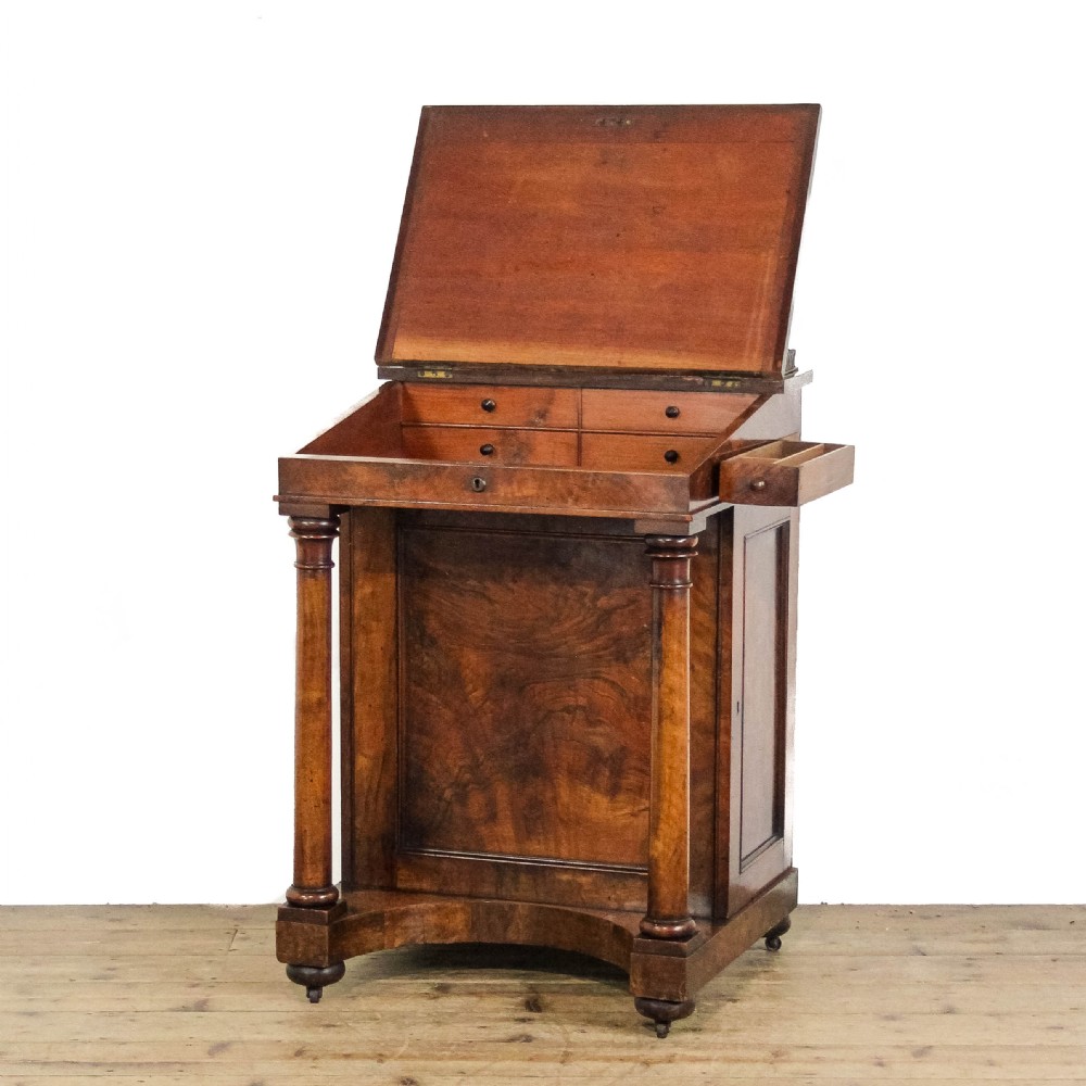An early 19th-century mahogany davenport desk featuring a green leather writing slope, brass gallery top rail, turned front support columns, and an integrated drawer with a key. View V