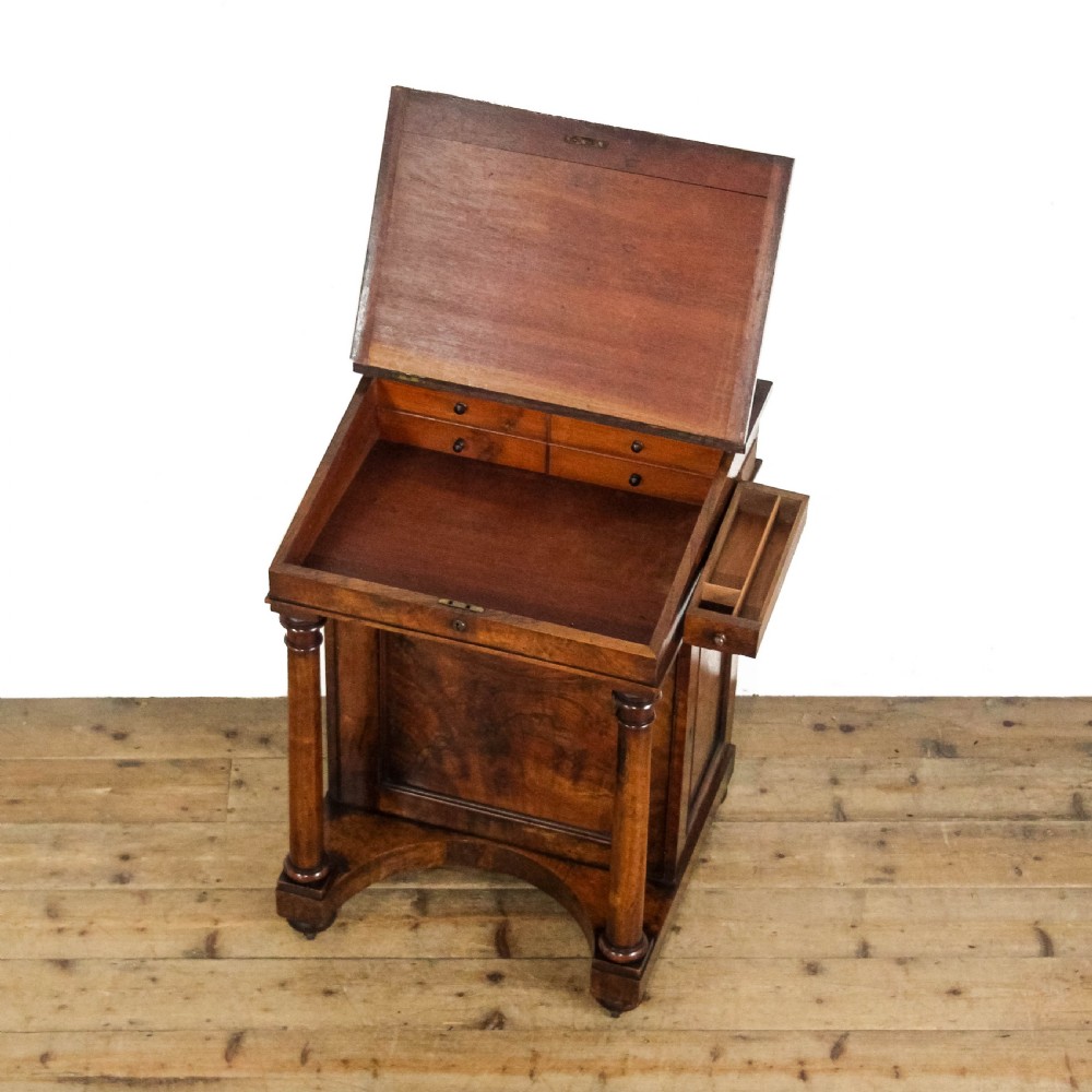 An early 19th-century mahogany davenport desk featuring a green leather writing slope, brass gallery top rail, turned front support columns, and an integrated drawer with a key. View VI