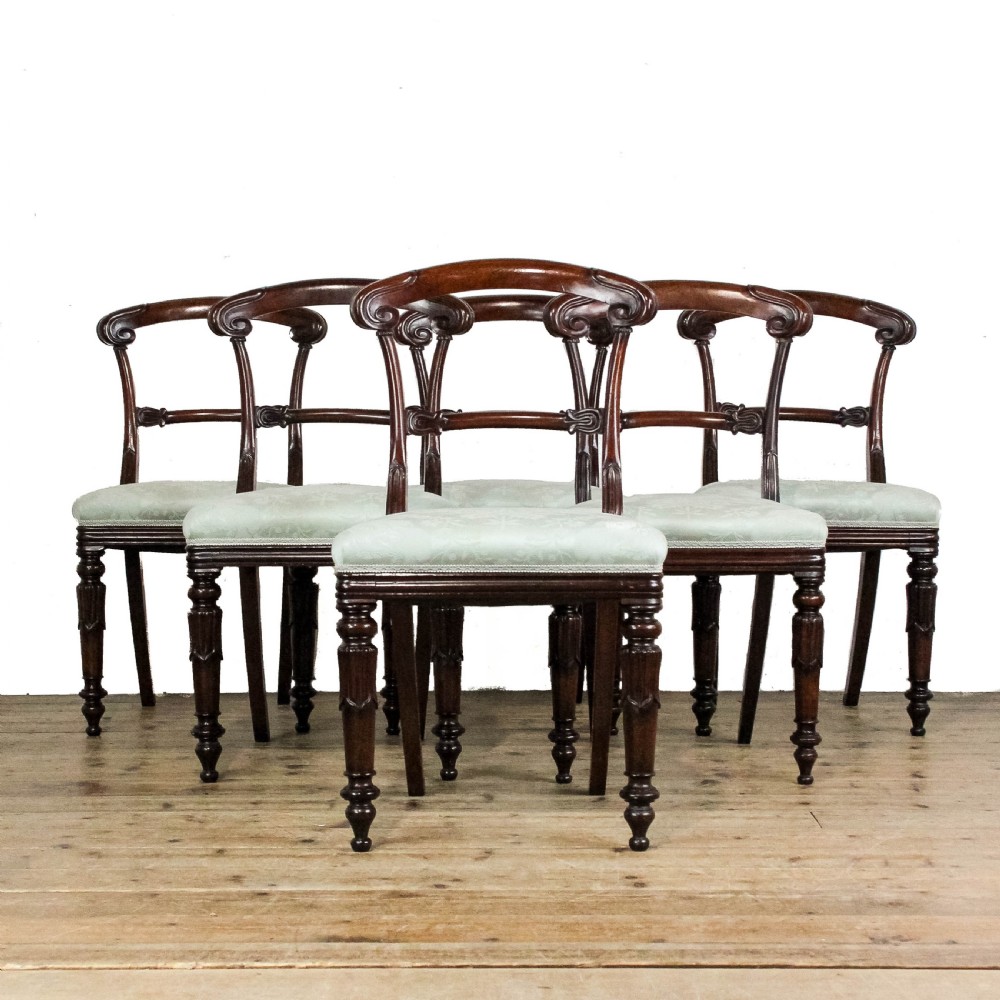A set of six Victorian mahogany dining chairs with carved scroll backrests and pale green fabric seats.