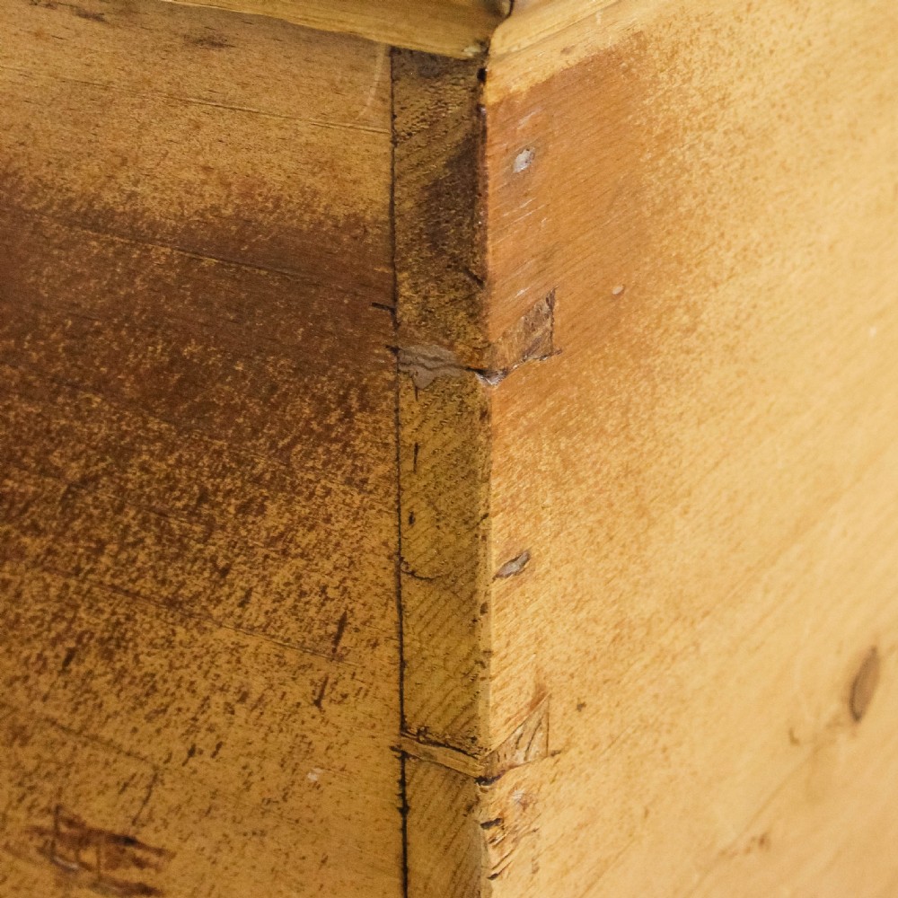 A rectangular antique pine blanket box featuring visible dovetail joinery, a brass keyhole escutcheon, and a shaped plinth base. View IV