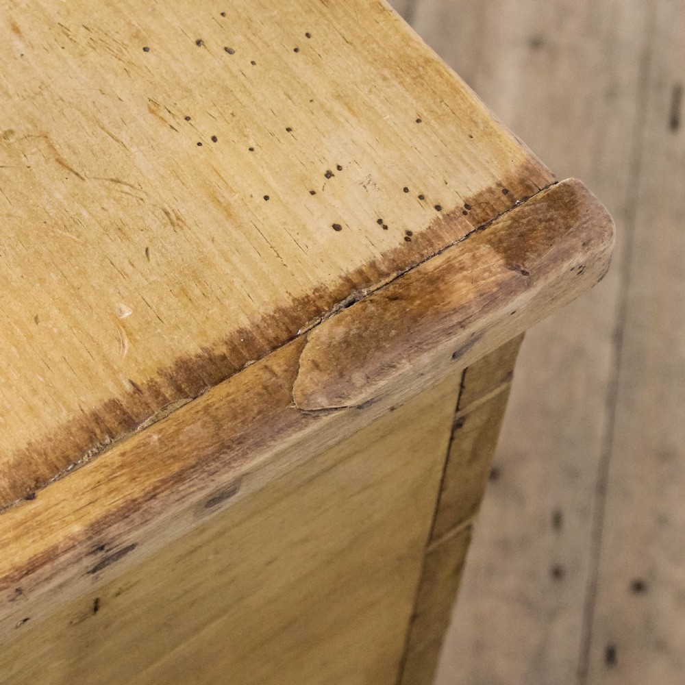 A rectangular antique pine blanket box featuring visible dovetail joinery, a brass keyhole escutcheon, and a shaped plinth base. View V