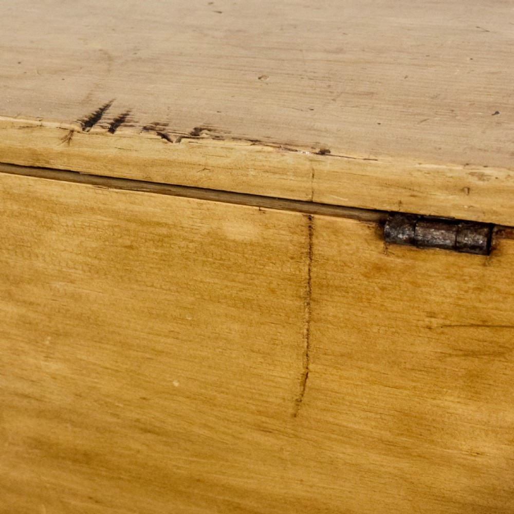 A rectangular antique pine blanket box featuring visible dovetail joinery, a brass keyhole escutcheon, and a shaped plinth base. View IX