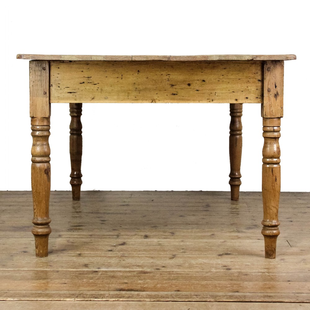 A large antique pine farmhouse kitchen table featuring a plank top, turned legs, and a single frieze drawer with a wooden knob. View X