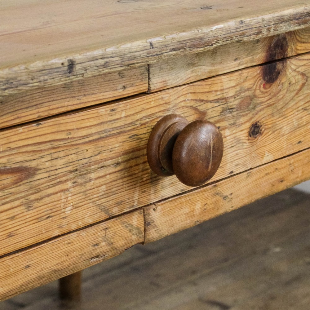A large antique pine farmhouse kitchen table featuring a plank top, turned legs, and a single frieze drawer with a wooden knob. View XII