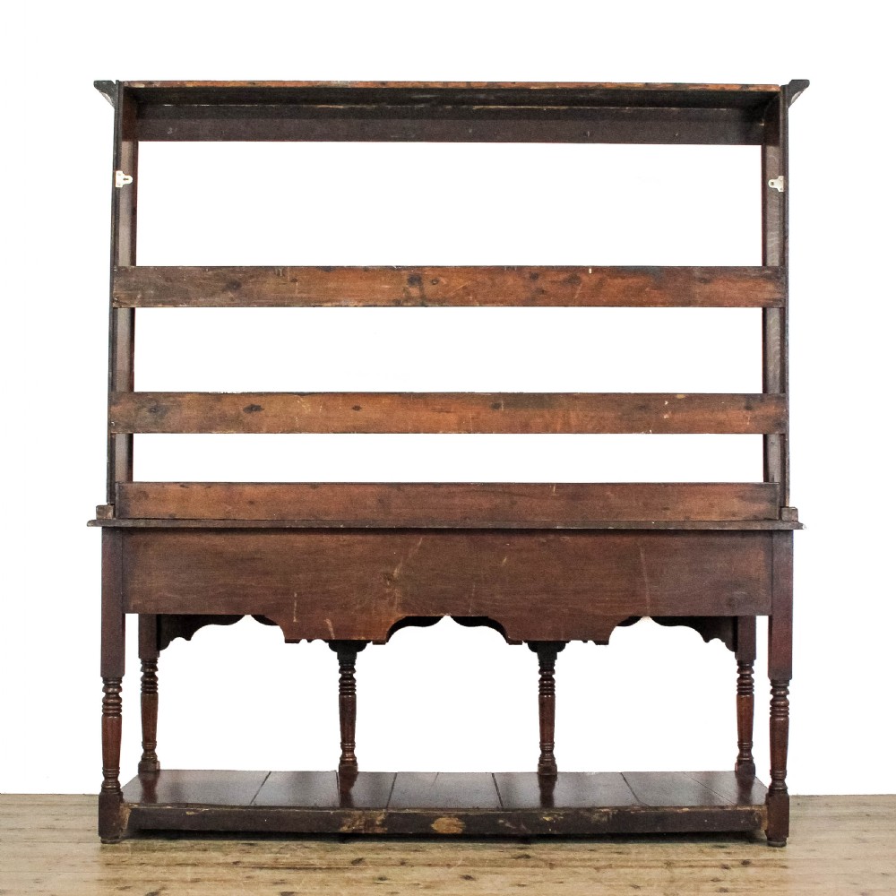 An 18th-century Welsh oak dresser featuring a three-shelf open plate rack with cup hooks, five small spice drawers, three main drawers with brass handles, a shaped apron, turned front supports, and a lower potboard shelf. View III