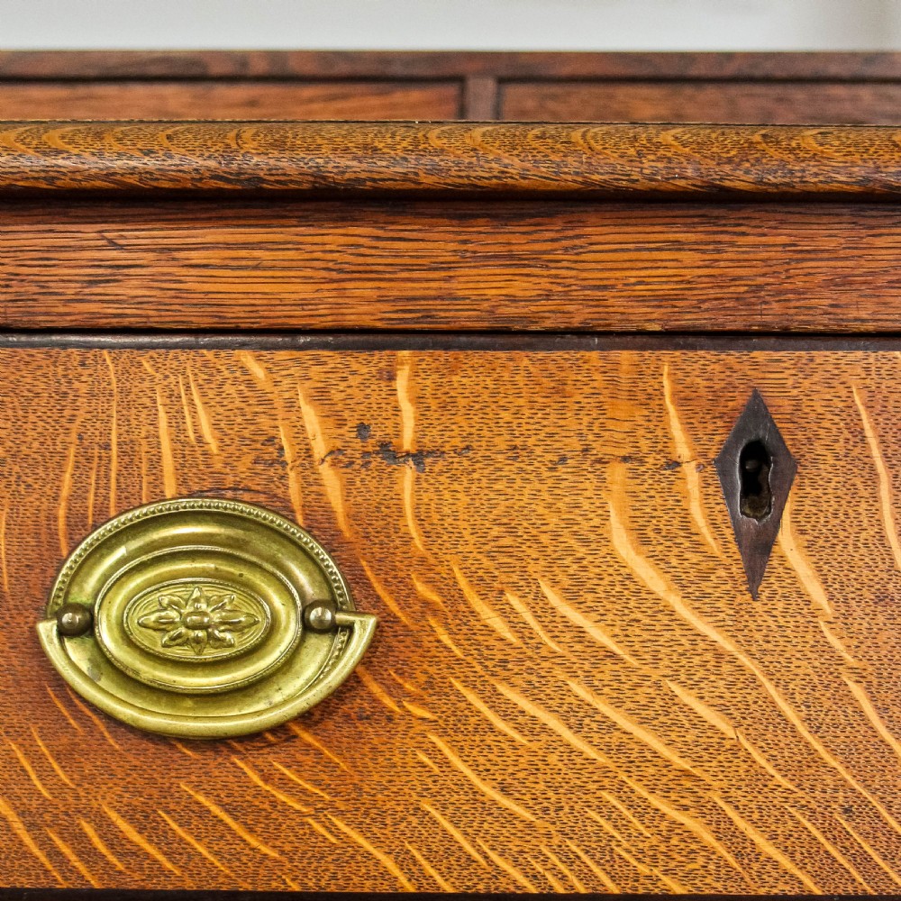 An 18th-century Welsh oak dresser featuring a three-shelf open plate rack with cup hooks, five small spice drawers, three main drawers with brass handles, a shaped apron, turned front supports, and a lower potboard shelf. View IX