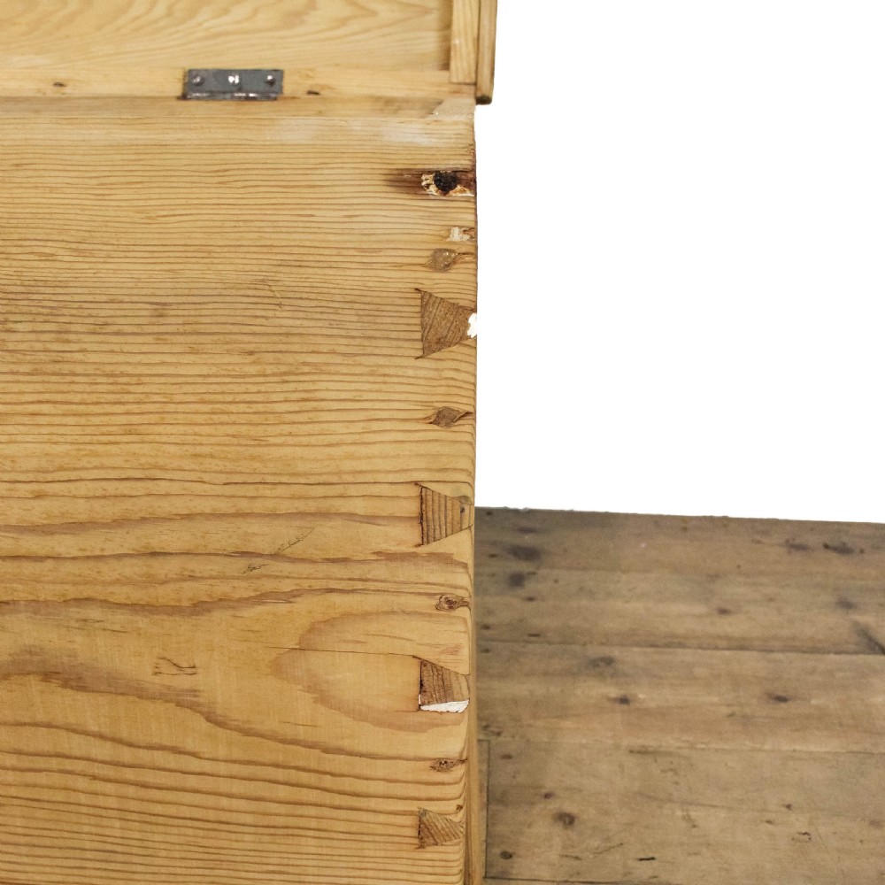 A natural pine storage trunk featuring a gently domed top lid, exposed dovetail corner joints, and a central circular brass escutcheon. View XI