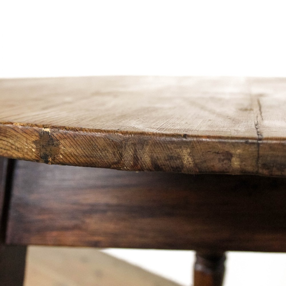 An antique circular pine cricket table with three turned wooden legs and a deep triangular apron beneath the tabletop. View III