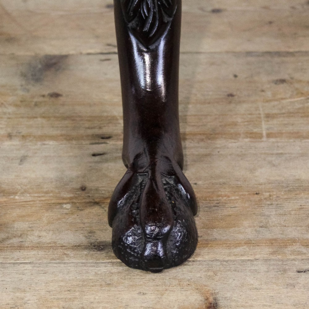 A dark mahogany tilt-top tripod table featuring an intricately carved circular top with a floral vase motif, supported on three carved legs. View III