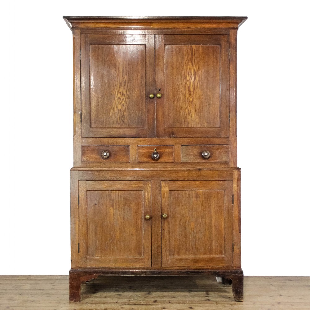 A 19th-century oak linen press featuring two top panelled doors, three central drawers, and a lower double-door cupboard on bracket feet.