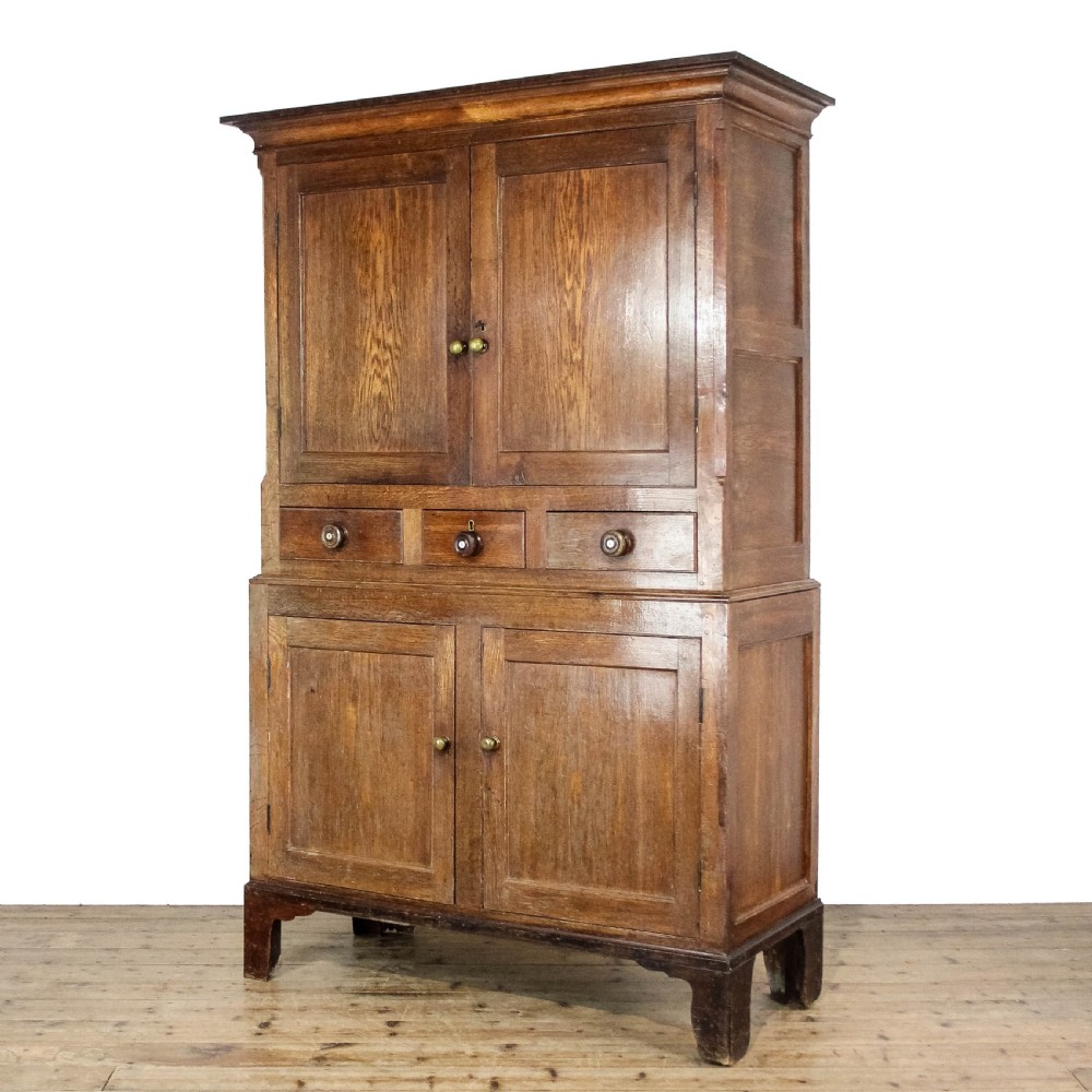 A 19th-century oak linen press featuring two top panelled doors, three central drawers, and a lower double-door cupboard on bracket feet. View II