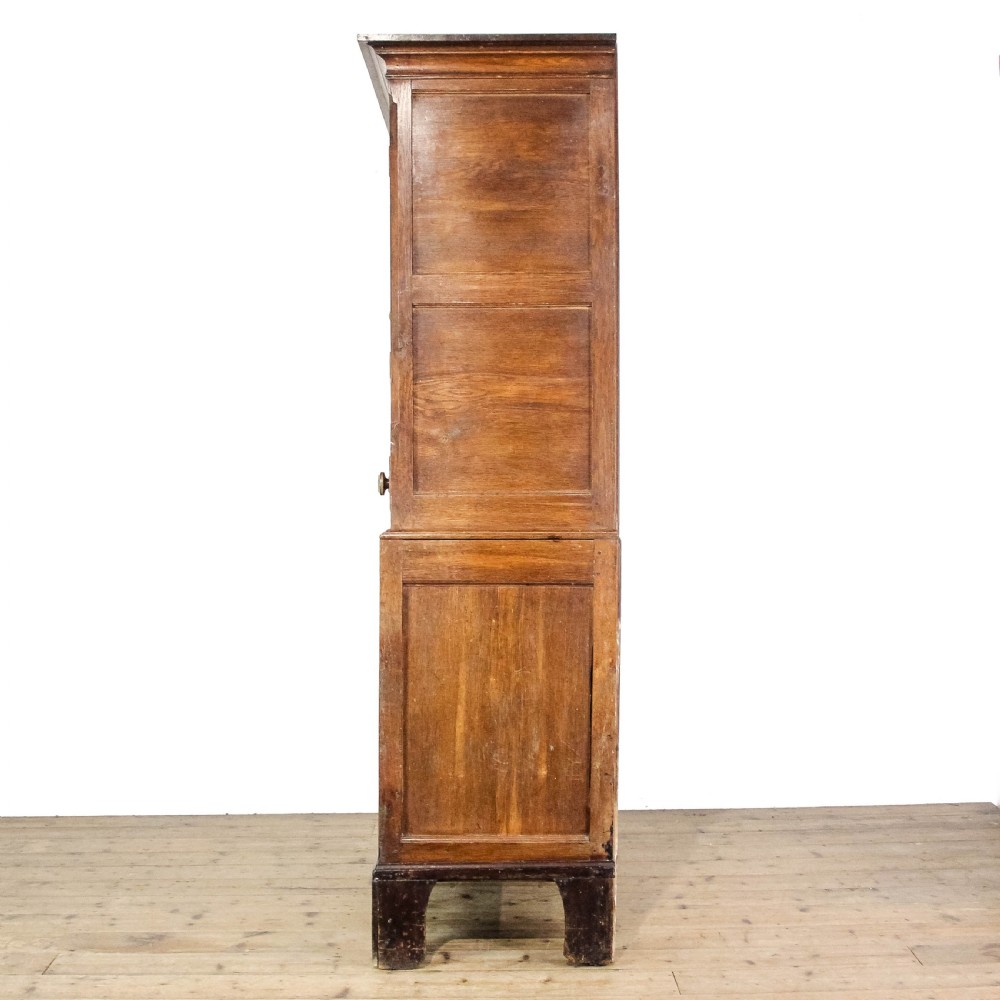 A 19th-century oak linen press featuring two top panelled doors, three central drawers, and a lower double-door cupboard on bracket feet. View III