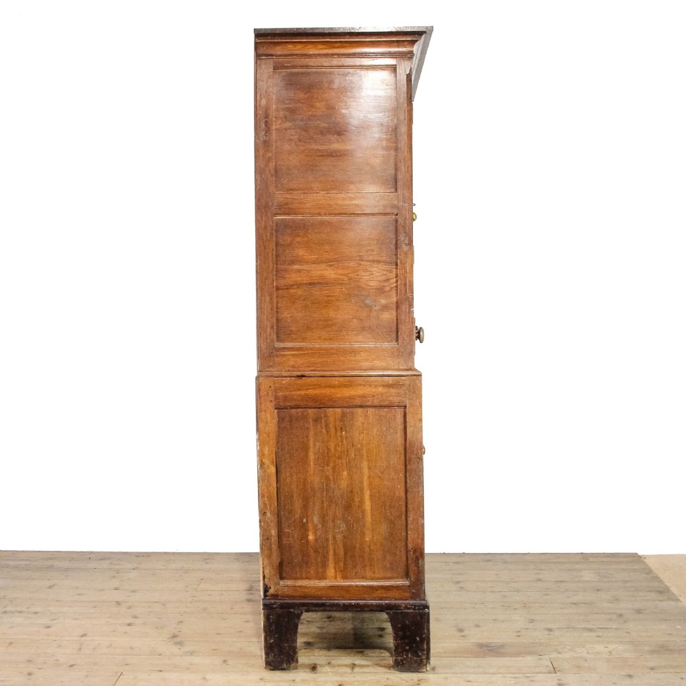 A 19th-century oak linen press featuring two top panelled doors, three central drawers, and a lower double-door cupboard on bracket feet. View IV