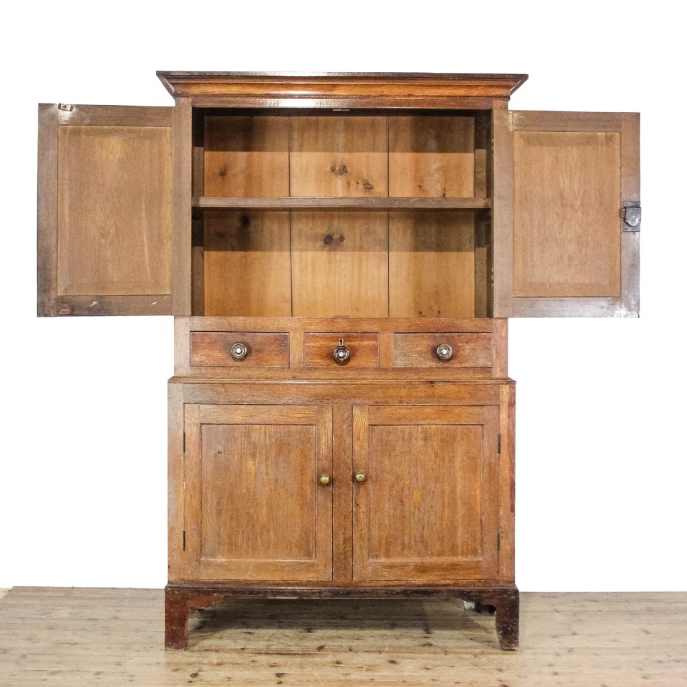A 19th-century oak linen press featuring two top panelled doors, three central drawers, and a lower double-door cupboard on bracket feet. View VI