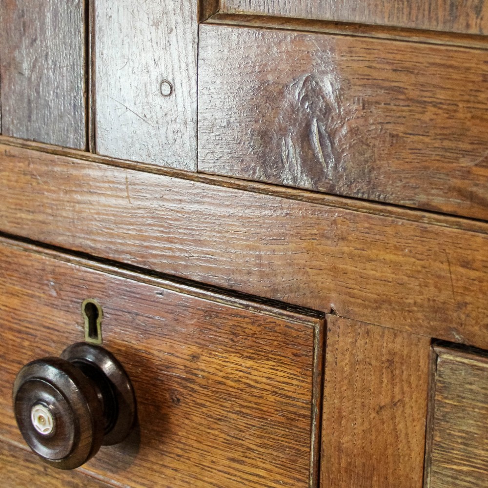 A 19th-century oak linen press featuring two top panelled doors, three central drawers, and a lower double-door cupboard on bracket feet. View VII