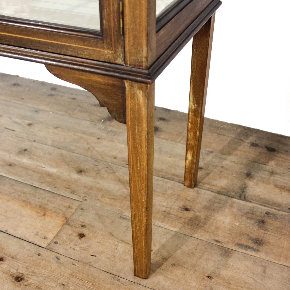 An antique Edwardian mahogany display cabinet featuring inlaid garland swags on the top frieze, twin glazed doors with gothic astragal bars, and slender square legs. View IV