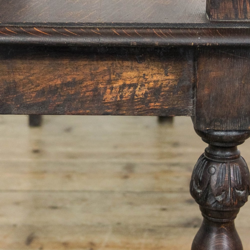 A dark carved oak hall bench featuring turned front legs, shaped armrests, and an open carved backrest. View VII