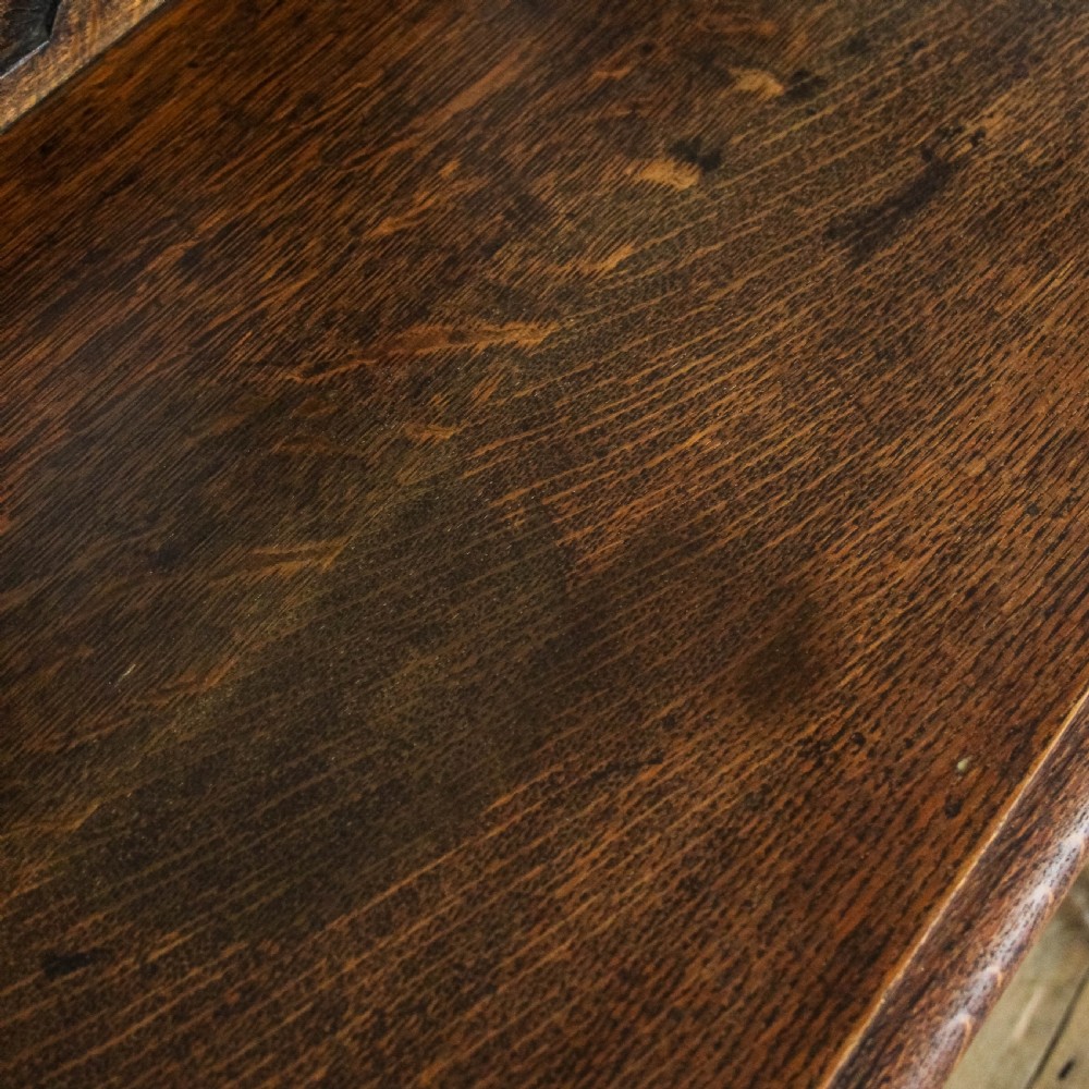 A dark carved oak hall bench featuring turned front legs, shaped armrests, and an open carved backrest. View VIII