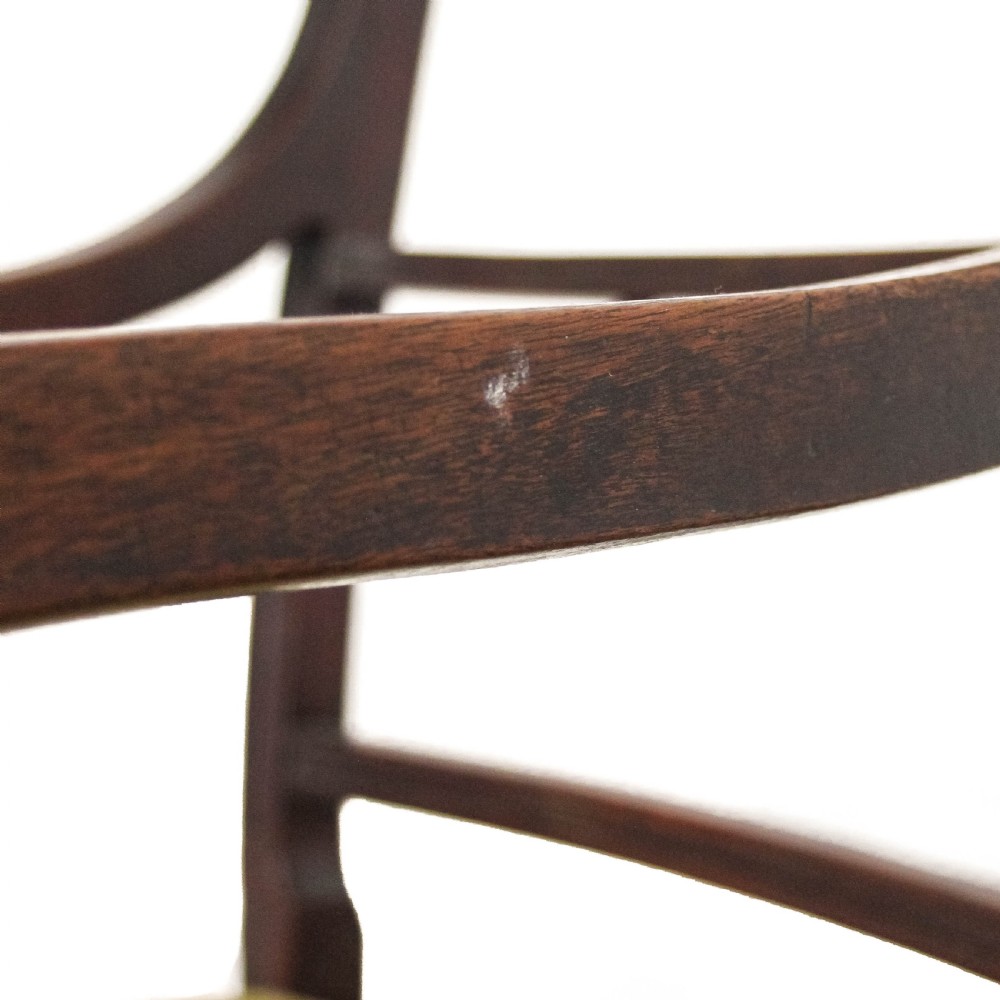 An antique dark mahogany commode chair featuring turned arm supports, a bar back frame, and an olive green drop-in seat pad. View XI