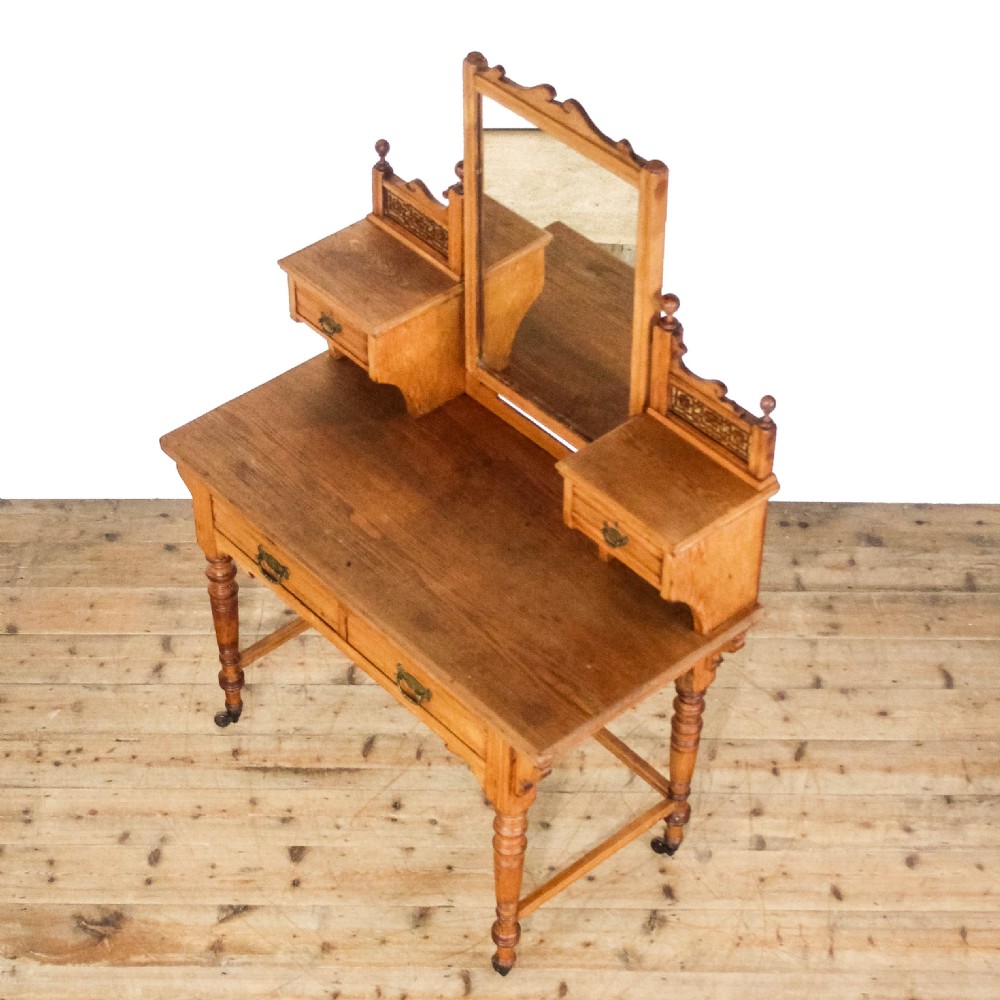 An antique Edwardian pine dressing table featuring a central swinging mirror, raised trinket drawers with pierced galleries, two lower drawers, turned legs, and brass castors. View VIII