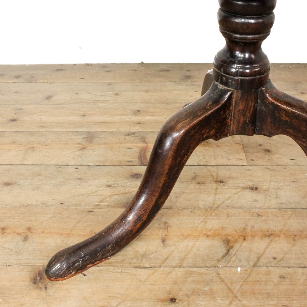 A Georgian dark oak tilt top table featuring a circular surface, ring-turned central column, and three down-swept tripod legs. View III