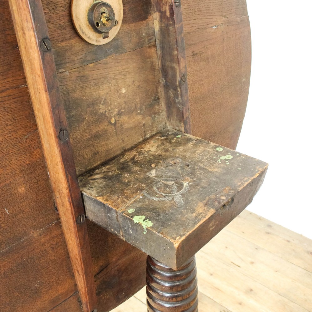 A Georgian dark oak tilt top table featuring a circular surface, ring-turned central column, and three down-swept tripod legs. View VI
