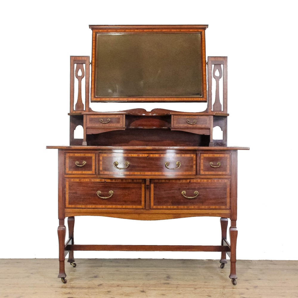 An Edwardian mahogany dressing table featuring satinwood marquetry inlay, a central swivel mirror, elevated jewellery drawers, and lower storage drawers with brass drop handles.