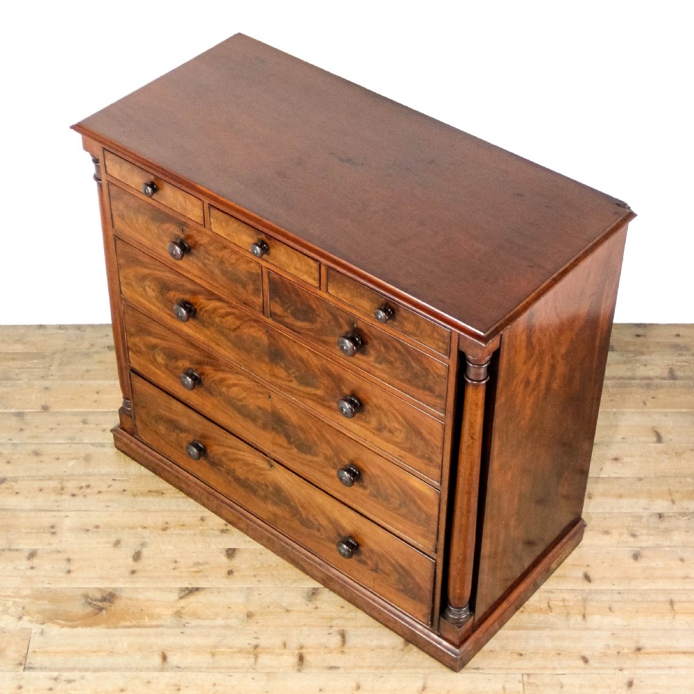 A large Victorian flame mahogany chest of drawers featuring turned wooden handles, flanking turned columns, and a solid plinth base. View V
