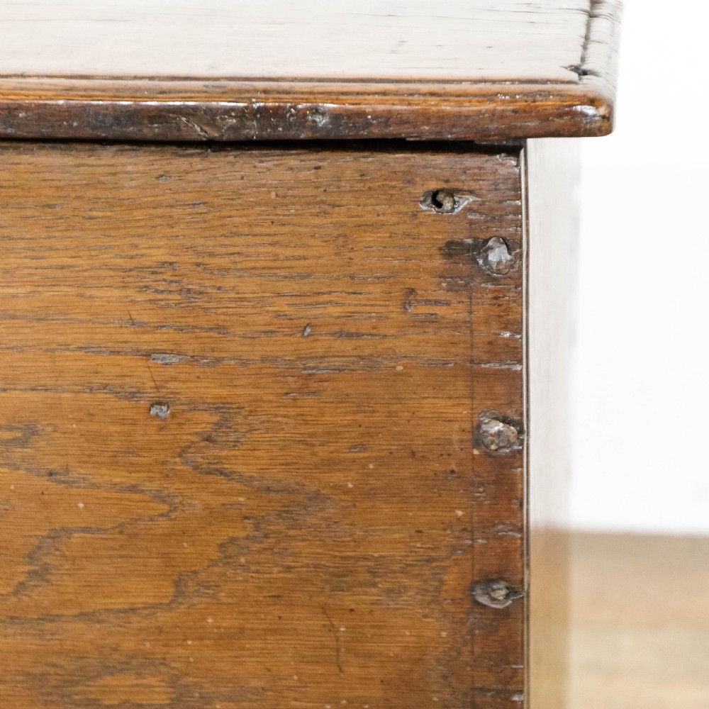 An 18th-century solid oak sword chest featuring a rectangular lift-top lid, iron lockplate, and cutout side supports. View IX