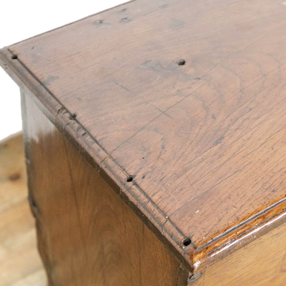 An 18th-century solid oak sword chest featuring a rectangular lift-top lid, iron lockplate, and cutout side supports. View X