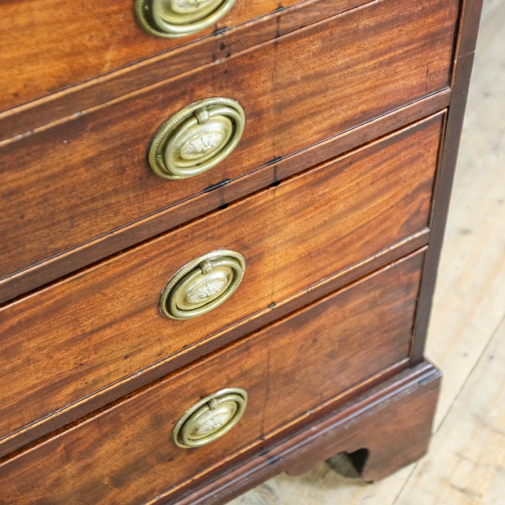 An antique mahogany writing bureau with a slant-front fall, four graduated drawers, oval brass handles, and bracket feet. View XII