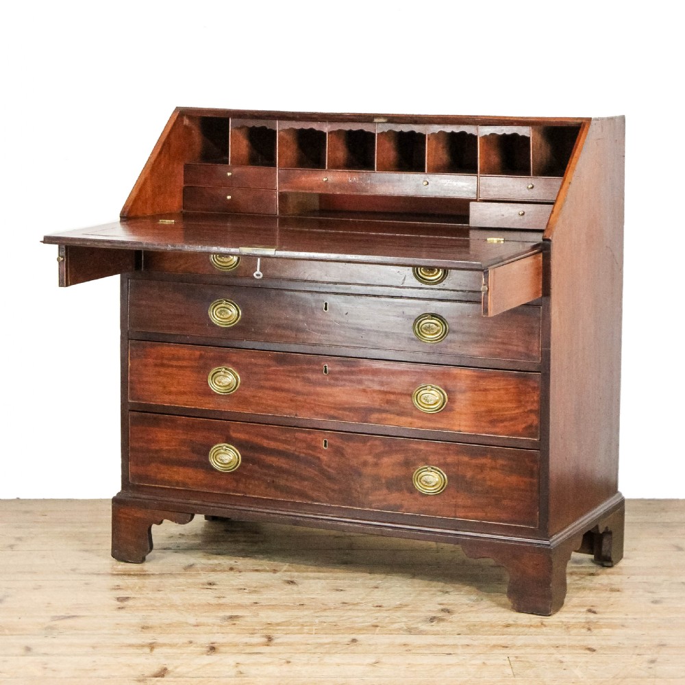 An antique mahogany writing bureau with a slant-front fall, four graduated drawers, oval brass handles, and bracket feet. View XIII