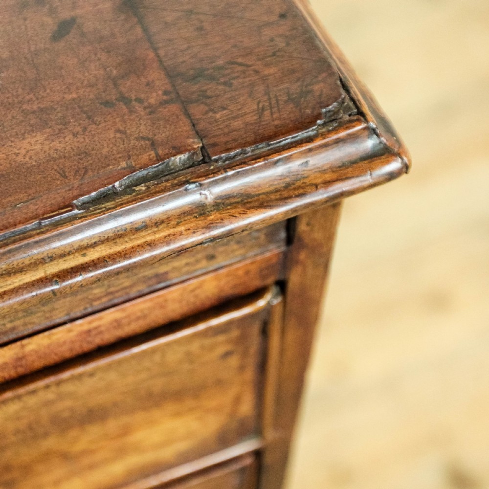 A Georgian mahogany bachelors chest of drawers featuring four graduated drawers with brass handles and a pull-out brushing slide set on bracket feet. View X