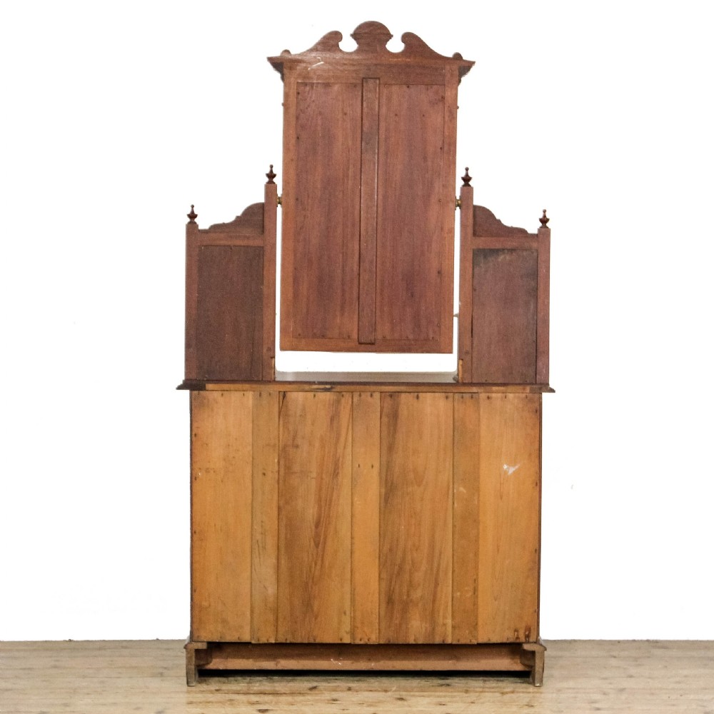A Victorian carved oak dressing chest featuring an upper mirror superstructure with small side drawers and a lower three-tier chest of drawers on a plinth base. View V
