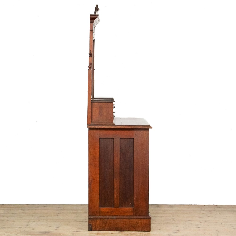 A Victorian carved oak dressing chest featuring an upper mirror superstructure with small side drawers and a lower three-tier chest of drawers on a plinth base. View VI