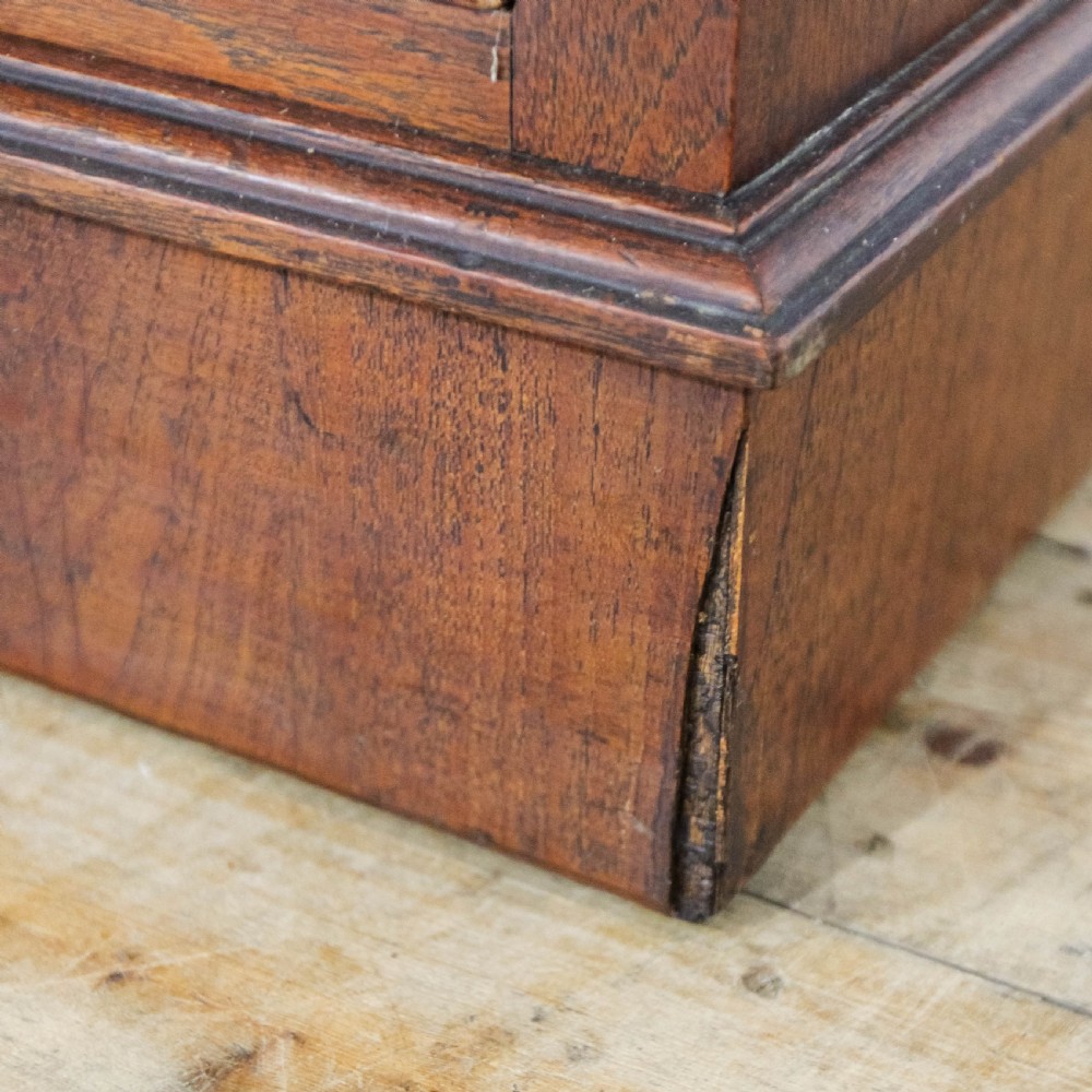 A Victorian carved oak dressing chest featuring an upper mirror superstructure with small side drawers and a lower three-tier chest of drawers on a plinth base. View XI