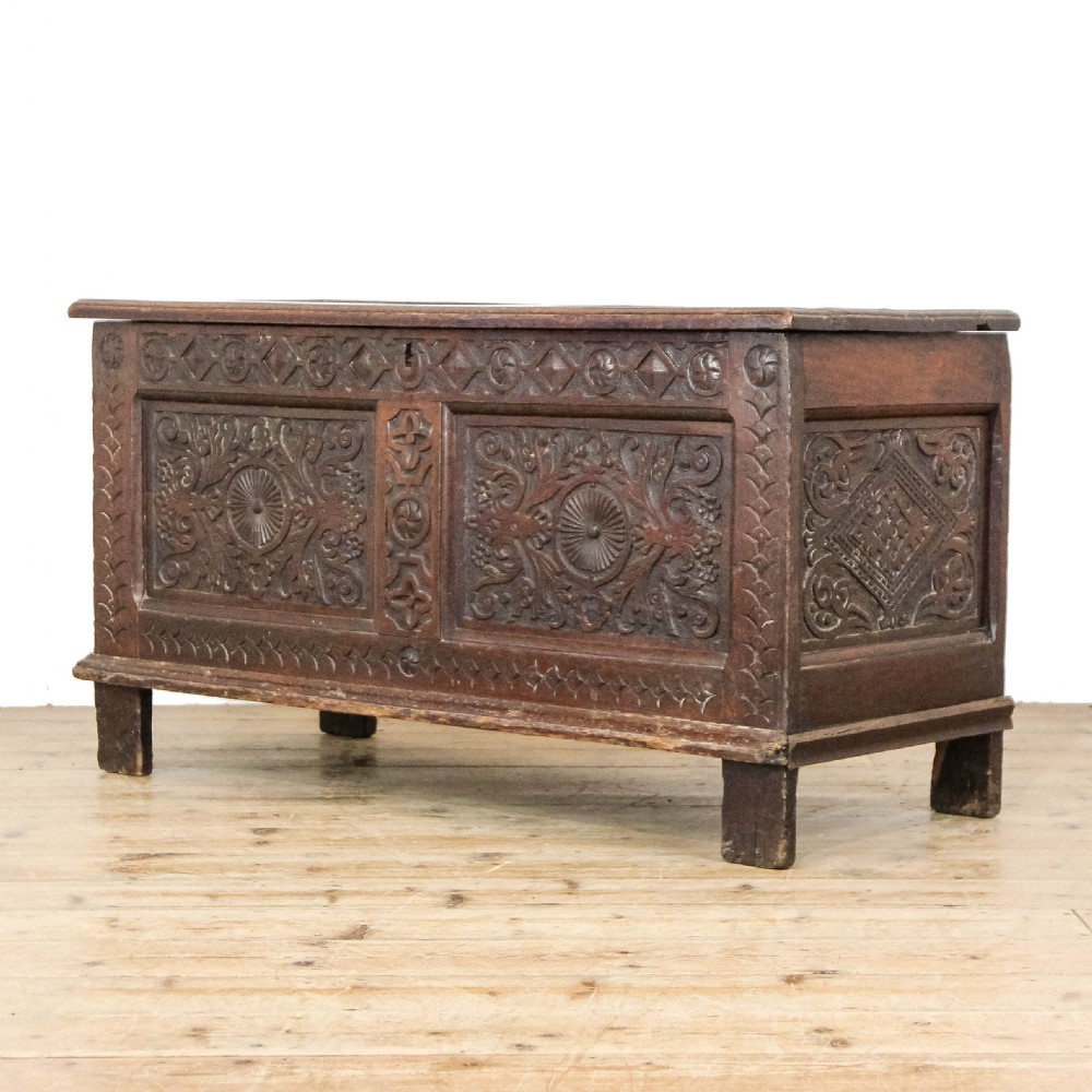 A 19th-century dark oak coffer featuring carved floral scroll panels, a decorative frieze, and sturdy block feet. View II