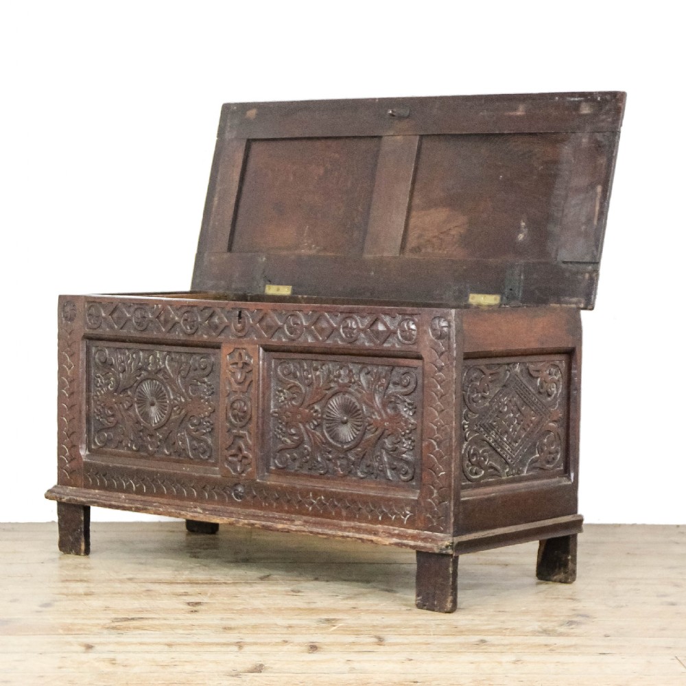 A 19th-century dark oak coffer featuring carved floral scroll panels, a decorative frieze, and sturdy block feet. View III