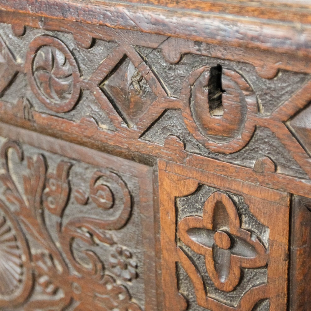 A 19th-century dark oak coffer featuring carved floral scroll panels, a decorative frieze, and sturdy block feet. View X