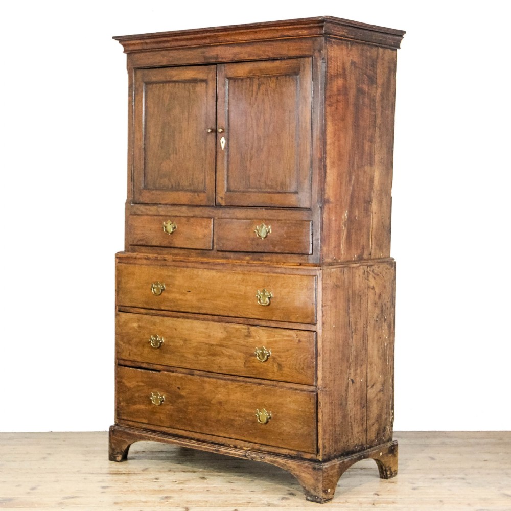 A nineteenth-century two-part oak housekeepers cupboard featuring twin panelled upper doors above two short and three long drawers with brass hardware. View II