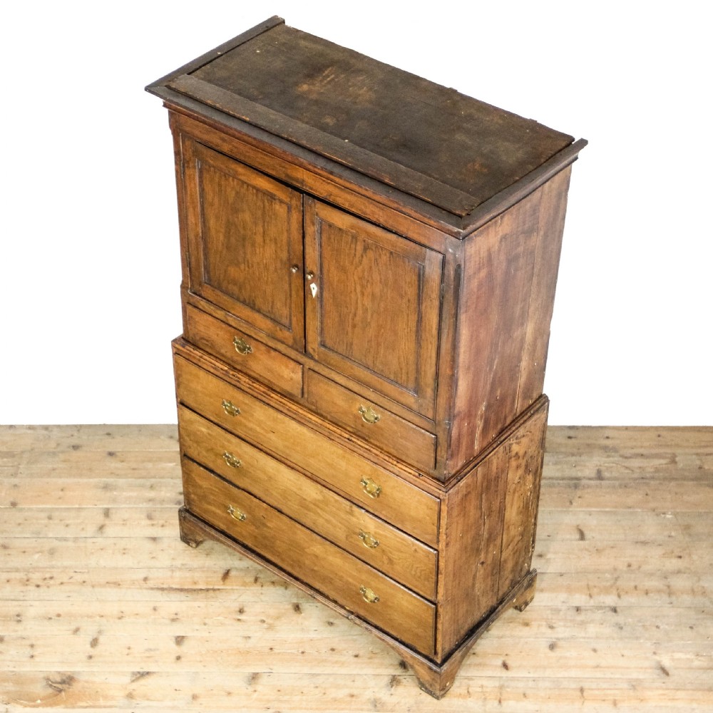 A nineteenth-century two-part oak housekeepers cupboard featuring twin panelled upper doors above two short and three long drawers with brass hardware. View VI